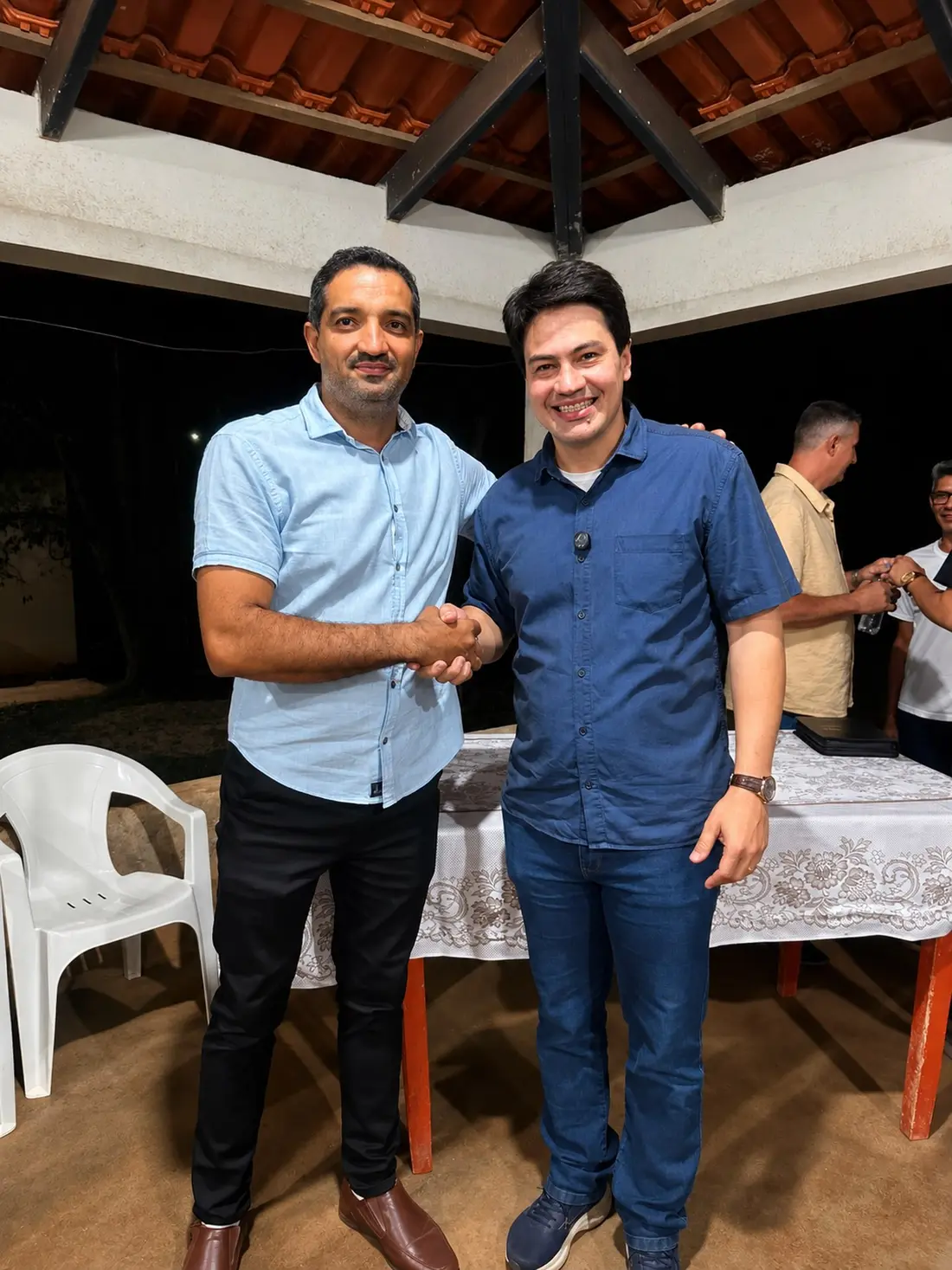 Aperto de mão entre Florismar Júnior e apoiador em evento noturno